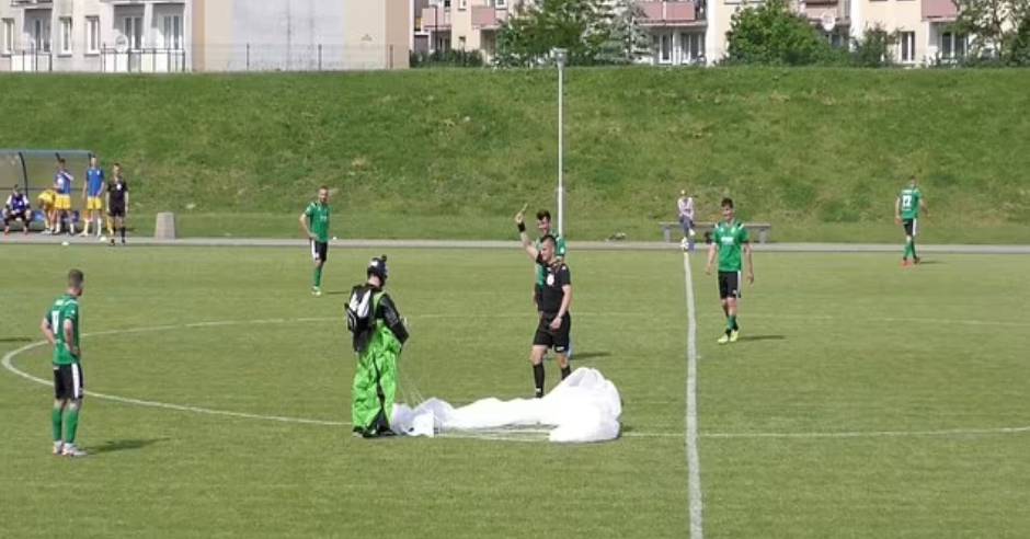 Parachutist lands on a football pitch during a match in Poland