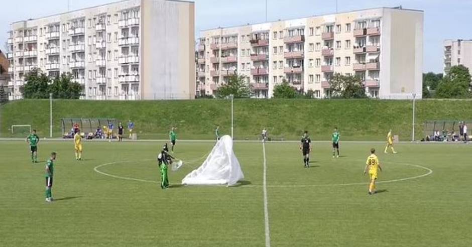 Parachutist lands on a football pitch during a match in Poland