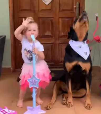 Dog and little girl are singing sisters in concert