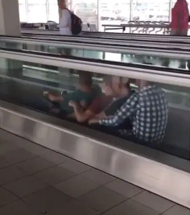 4 men rowing on a moving walkway at the airport